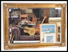 A contemporary antique style wall mirror having gilt cushion frame with bevelled plate mirror glass.