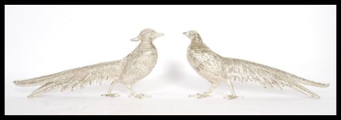 A pair of white metal figurines in the form of pheasants to include a male and a female. Measures 13