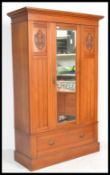 An early 20th Century satin walnut single wardrobe having a central mirror panel door flanked by
