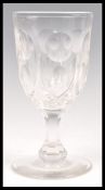 A large 19th Century faceted glass wine glass of tall form raised on a circular foot with faceted