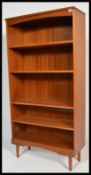 A vintage retro 20th Century teak wood tall bookcase cabinet raised on tapering legs with fitted