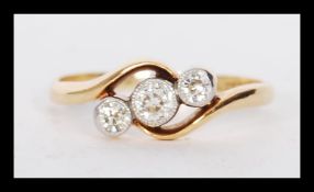 A stamped 18ct gold crossover ring millegrain set with three diamonds. Weight 2.3g. Estimated