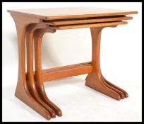A retro 20th Century Danish influence teak wood nest of three graduating tables, raised on L- shaped
