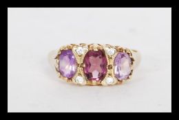 A hallmarked 9ct gold three stone amethyst ring in a Gypsy setting having white stones spacers.