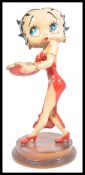 A large figure of Betty Boop raised on circular wooden base. The iconic character in red dress.