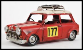 A vintage tin plate model car rally racing Mini, having a with a red painted finish, white racing