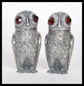 A pair of stamped 800 silver condiments in the form of owls set with faceted red stone eyes.