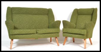 A mid century sofa and matching armchair in the manner of Howard Keith. Raised on turned tapering