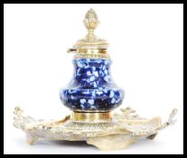 A 19th Century Victorian gilt brass and ceramic inkwell and stand having a large square pierced base