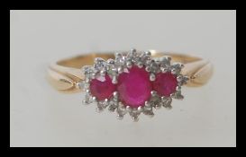 A hallmarked 9ct gold diamond and ruby triple squashed cluster ring having 23 stones consisting of