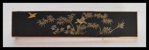 A Japanese brooch having a rectangular panel with decorated gilt birds on bamboo in a gold casing,