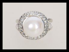 A stamped 925 silver ring set with a large pearl surrounded by cz accent stones having rope twist