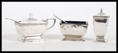 An early 20th Century hallmarked silver three piece condiment cruet set consisting of lidded mustard