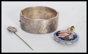 A silver hallmarked bangle bracelet having scrolled foliate and greek key engraving with a hinged