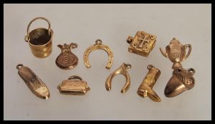 A collection of hallmarked 9ct gold charms, to include a horseshoe, wish bone, bible, money bag,