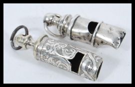 Two whistles to include a hallmarked silver whistle and a silver plated example with rococo chased