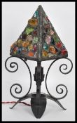 A 20th Century iron scrollwork table lamp, the lamp raised on four downward swept leaf base with
