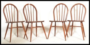 A set of four 1960's ercol beech wood hoop back dining chairs having tapering supports finish in