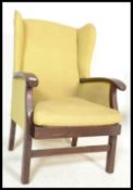 A retro 20th Century Parker Knoll style wing back arm chair having a dark wood show frame raised