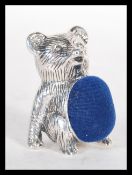 A silver pincushion in the form of a teddy bear ha