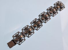 A vintage 20th century silver 6 panel bracelet decorated with flowerheads, scrolls and beads.