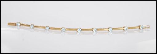 A hallmarked 9ct gold spacer bracelet prong set with round cut light blue stones. Hallmarked