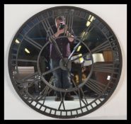 A large contemporary ebonised iron framed skeleton wall clock, mirrored backed and iron roman
