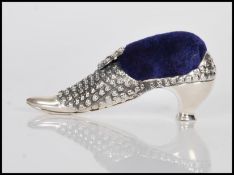A sterling silver Victorian style pincushion in the form of a shoe having embossed decoration,