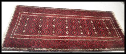 A 20th Century Persian / Islamic carpet floor rug / runner, having a red ground with medallions to