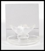A Lalique pin dish, circular base surmounted by kissing doves, signed, within original retailers