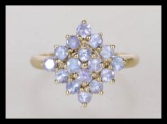 A hallmarked 9ct gold ladies cluster ring prong set with lilac stones in a geometric formation.
