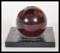 A vintage Schweppes pub advertising pen holder having an ebonised square base with a spherical resin