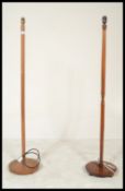 A pair of retro 20th Century teak wood standard lamps raised on terraced bases with turned