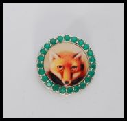 A silver brooch / pendant having central porcelain panel depicting a fox, with a halo of green
