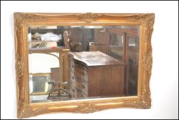 A large 20th century antique style gilt framed mirror. The gilded cushion frame having an inset