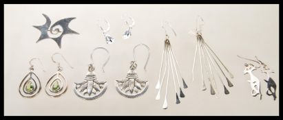 A collection of silver earrings including drop earrings with green stones, a pair of stamped 925