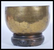 An early 20th Century hand worked buddhist  brass temple bowl of globular form, raised on a circular