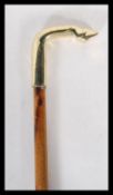 A walking stick cane having a brass horse hoof/ foot top on a bamboo shaft, having carved wording.