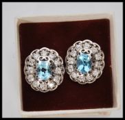 A pair of ladies silver dress earrings prong set with oval cut blue topaz stones with a halo of cz's