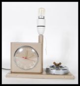 A vintage retro mid century bedside alarm clock lamp and ashtray combination, being finished in an