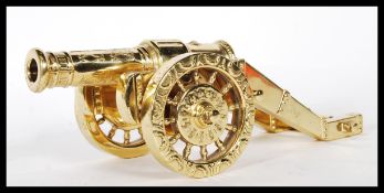 A 20th Century gilt brass desktop cannon ornament having twin wheels with raised garland