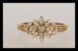 A stamped 375 9ct gold ring having a flower head set with white accent stones. Weight 2.5g.