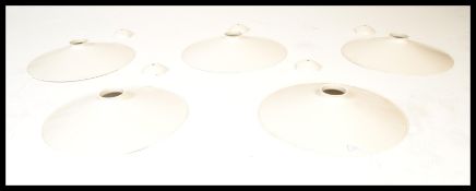A group of five retro industrial factory style UFO form lampshades having white enamelled finish.