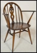 An original mid 20th century beech and elm Ercol Fleur De Lys pattern armchair having shaped elbow
