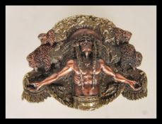 A cast metal belt buckle having raised decoration of a Native American having outstretched arms