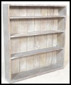 An early 20th Century oak limed open bookcase, adjustable shelves to the interior raised on a plinth