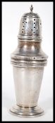 A silver hallmarked sugar shaker of tapering cylindrical form being raised on a stepped round base