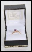 A 9ct gold and amethyst ring. Cross over setting with cushion cut amethyst. London import marks to