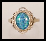 A hallmarked 9ct gold ladies dress ring set with a blue opalescent cabochon in a decorative setting.