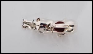 A sterling silver pincushion in the form of a stretching cat, having emerald eyes and baize pin
